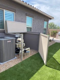 an air conditioner sitting in front of a house next to a green grass covered yard