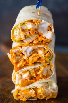 a stack of burritos sitting on top of a cutting board next to a blue toothpick