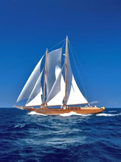 a sailboat sailing in the ocean on a sunny day with blue sky and white sails