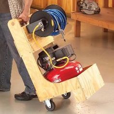 a man holding a cart with an air compressor attached to it