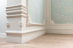 the corner of an empty room with wood floors and blue wall paper on the walls