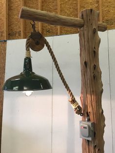 a wooden pole with a light hanging from it's side next to a wall