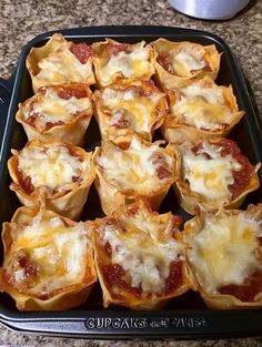 several mini pizzas with cheese and sauce in a baking pan on a counter top