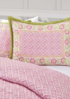 a bed with pink and green pillows on top of it