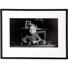 a black and white photo of a young boy sitting at a table with blocks in front of him