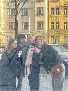 four people standing in the snow with their hands together