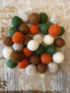 a pile of wool balls sitting on top of a white towel covered in green and orange felt