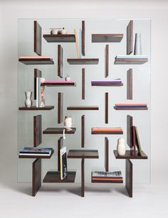 a book shelf with books and vases on top of it in front of a mirrored wall