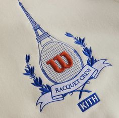 a white shirt with the eiffel tower on it's chest and an orange letter that reads racquet city