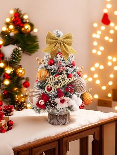 a small christmas tree sitting on top of a wooden table in front of some lights