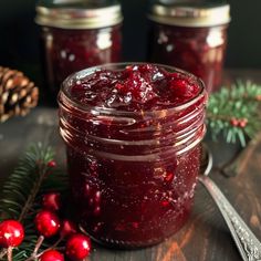 cranberry sauce in a glass jar with spoon and pine cones on the side