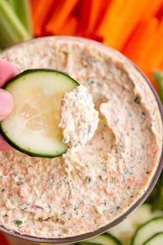 a hand dipping a cucumber into a bowl of dip with the words, veggie cream cheese