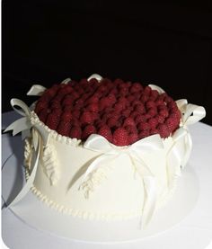 a white cake topped with raspberries on top of a table