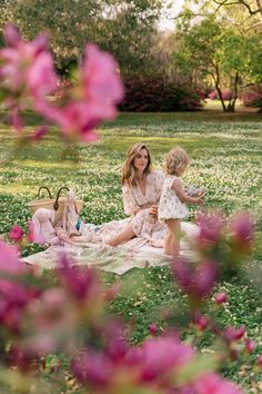 a mother and her daughter sitting on a blanket in the middle of a field full of flowers