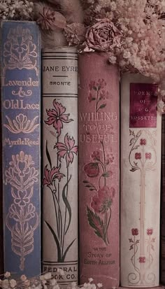 there are many books lined up on the shelf with flowers in them and one is pink