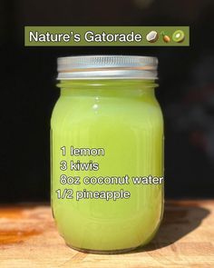 a mason jar filled with green liquid sitting on top of a wooden table