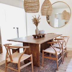 a dining room table with four chairs and a mirror on the wall above it, in front of a doorway