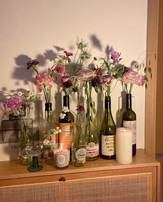 flowers in vases and bottles on a dresser