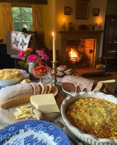 a table filled with food and candles on top of it next to a fire place