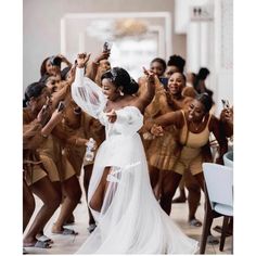 a group of women in white dresses dancing and posing for the camera with their arms up