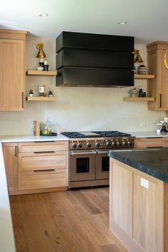 a kitchen with wooden cabinets and black range hood over the stove, along with wood flooring