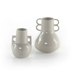 two white vases sitting next to each other on a white surface with holes in the middle