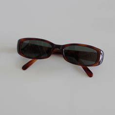 These slim rectangle sunglasses are your everyday classic. Featuring a red tortoise frame with smoke lens. This style is unisex. True genuine vintage sunglasses from the 90s.  - 400 uv  - new vintage from the 90s - includes sunglasses pouch  Measurements: Cheap Rectangular Tortoiseshell Sunglasses, Vintage Sunglasses Outfit, Sunglasses For Heart Shaped Face, Vintage Sunglasses Aesthetic, Random Accessories, Narrow Sunglasses, Autumn 23, 90s Sunglasses, Ralph Lauren Sunglasses