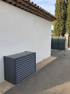 an air conditioner sitting on the side of a white wall next to a building