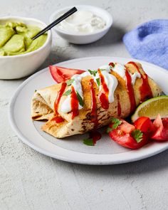 a white plate topped with food next to bowls of guacamole and strawberries