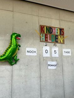 a green dinosaur balloon sitting on the side of a building next to a sign that says knickets hidden