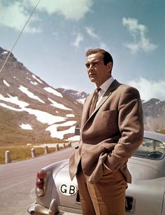 a man in a suit standing next to a car