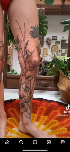 a woman's legs with tattoos on them and flowers in the bottom right leg