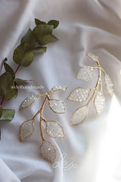 the gold leaves are attached to the white fabric with water droplets on them, and some green leaves