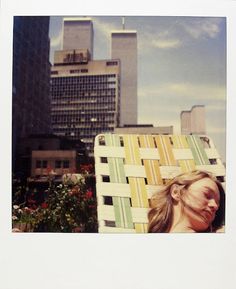 a polaroid photo of a woman sitting in a chair with buildings in the background