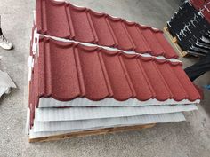 two men are standing next to some red roof tiles