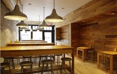 the interior of a restaurant with wooden tables and stools