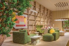 the interior of a modern office with green chairs and stools in front of bookshelves