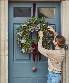 a woman placing a wreath on the front door