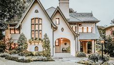 a large white house with lots of windows and plants on the front lawn in front of it