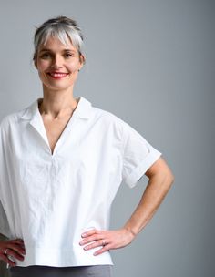 a woman standing with her hands on her hips and looking at the camera while wearing a white shirt