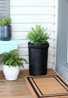 two potted plants sitting on the front porch next to a bench and door mat