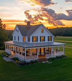 a large white house sitting on top of a lush green grass covered field under a cloudy sky