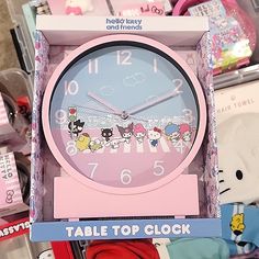 a pink clock with hello kitty characters on it's face in a display case