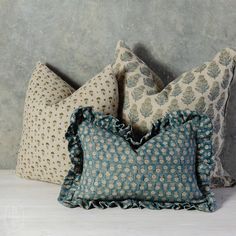 three decorative pillows with ruffled edges on a bed