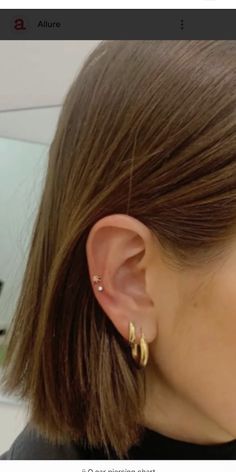 a close up of a person's ear wearing gold hoop earrings and black shirt