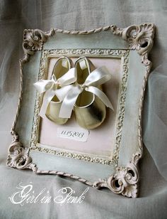 an ornate frame holds a pair of baby's shoes with a bow on it