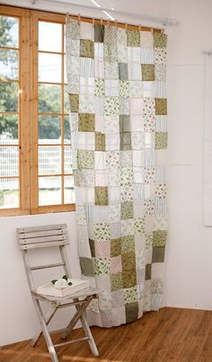 a chair sitting in front of a window next to a shower curtain with patchwork on it