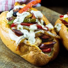 two hot dogs with toppings sitting on a cutting board