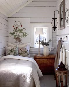 a bed sitting under a window next to a wooden table with a lamp on it