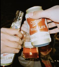 two people are holding beer cans in their hands